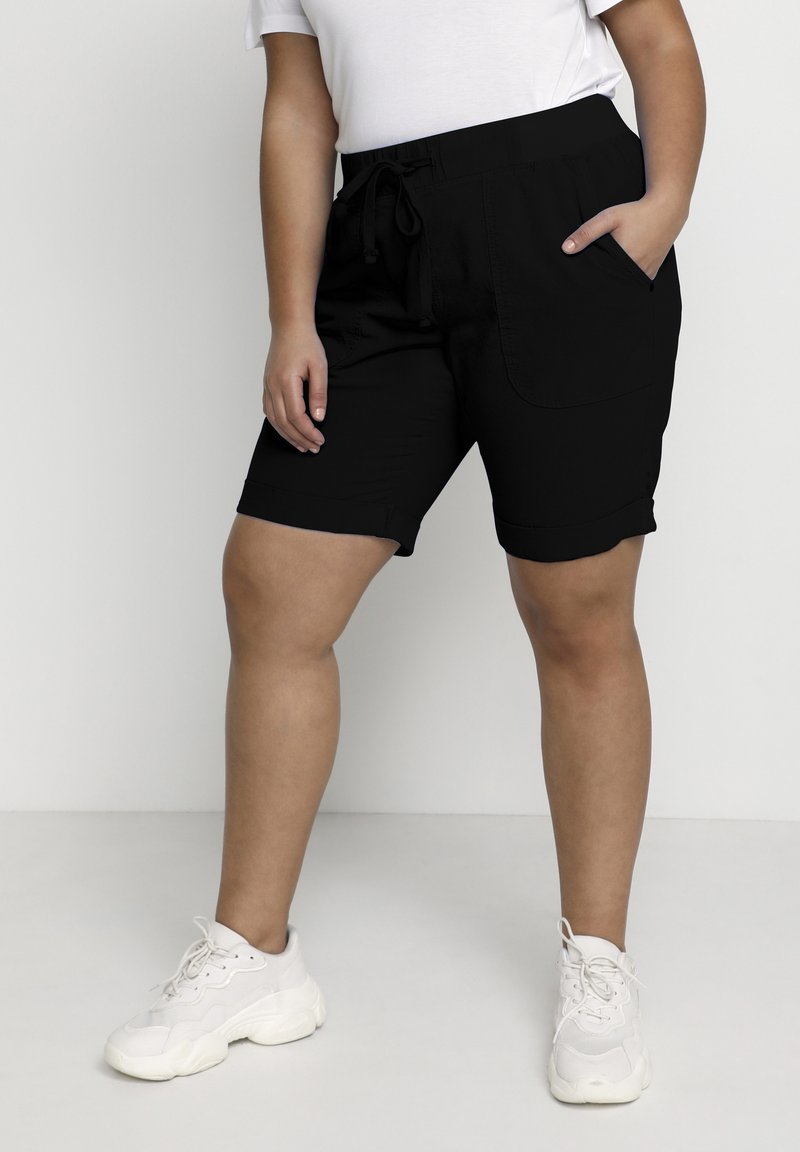 Black shorts with an elastic waistband and drawstring, featuring side pockets and rolled cuffs, worn with white sneakers.