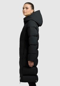 Zwarte pufferjas met capuchon, met een lange, gewatteerde stijl, ritszakken en een zachte, glanzende stofafwerking.