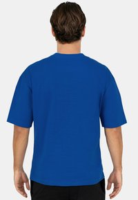 T-shirt en coton bleu à manches courtes, col rond et coupe décontractée. Texture lisse, sans motifs ni logos visibles.