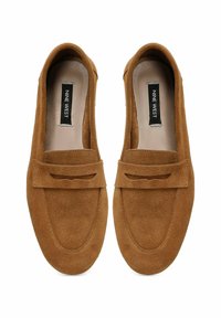 Brown suede loafers with a moccasin design, featuring a stitched toe and a decorative band. Flat sole, minimalist style, no visible hardware.