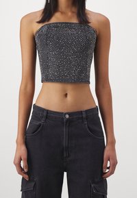 Svart strapless crop top med en figurnära design och spridda rhinestones. I kombination med hög midja mörka cargobyxor.