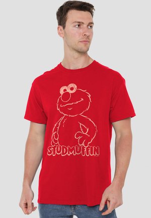 Rotes Baumwoll-T-Shirt mit einer Grafik von Elmo und dem Text "STUDMUFFIN" in Weiß darunter. Kurze Ärmel und Rundhalsausschnitt.