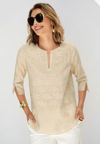 Beige Bluse mit strukturiertem Muster, Dreiviertelärmeln und V-Ausschnitt. Hergestellt aus leichtem Stoff mit dezentem Glanz.