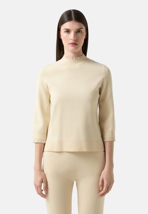Beige pletený svetr s dlouhým rukávem a vysokým žebrovaným límcem. Pletená textura a volný střih. Žebrovaný lem a manžety s hladkým povrchem po celém obvodu.