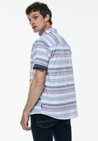 Košile s krátkým rukávem na knoflíky, se svislými pruhy v modré, červené a bílé barvě. Lehce materiál s volným střihem a kontrastními manžetami.