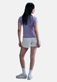 Korte mouwen lavendel t-shirt, aansluitend ontwerp, gecombineerd met witte geribbelde shorts. Witte sportschoenen en sokken maken de outfit compleet.
