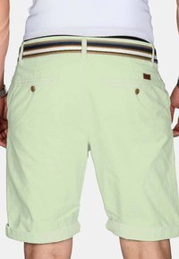 Light green shorts with a rolled hem, featuring back pockets and a multicolored woven belt with horizontal stripes.