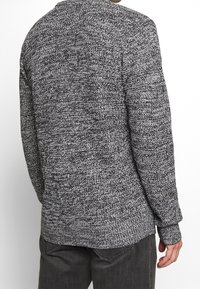 Pletený svetr s texturovaným vzorem v šedé a černé barvě, dlouhými rukávy, zaobleným výstřihem a žebrovanými manžetami a lemem.