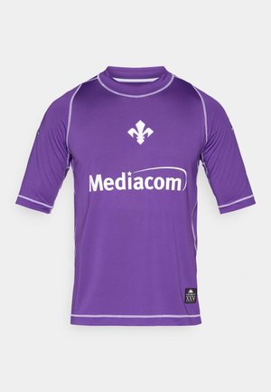 Lila Sporttrikot mit kurzen Ärmeln, weißen Akzenten und dem "Mediacom"-Logo. Enthält ein Wappen und ein Markenschild am Saum.