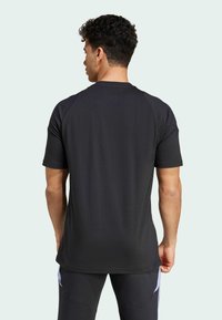 Kortærmet sort træningsshirt med en glat stofstruktur, raglanærmer og rund hals, båret af en model set bagfra.