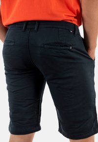 Donkerblauwe shorts met een slim fit, voorzien van achterzakken en een subtiele logodetail, gemaakt van lichtgewicht stof met een gladde textuur.