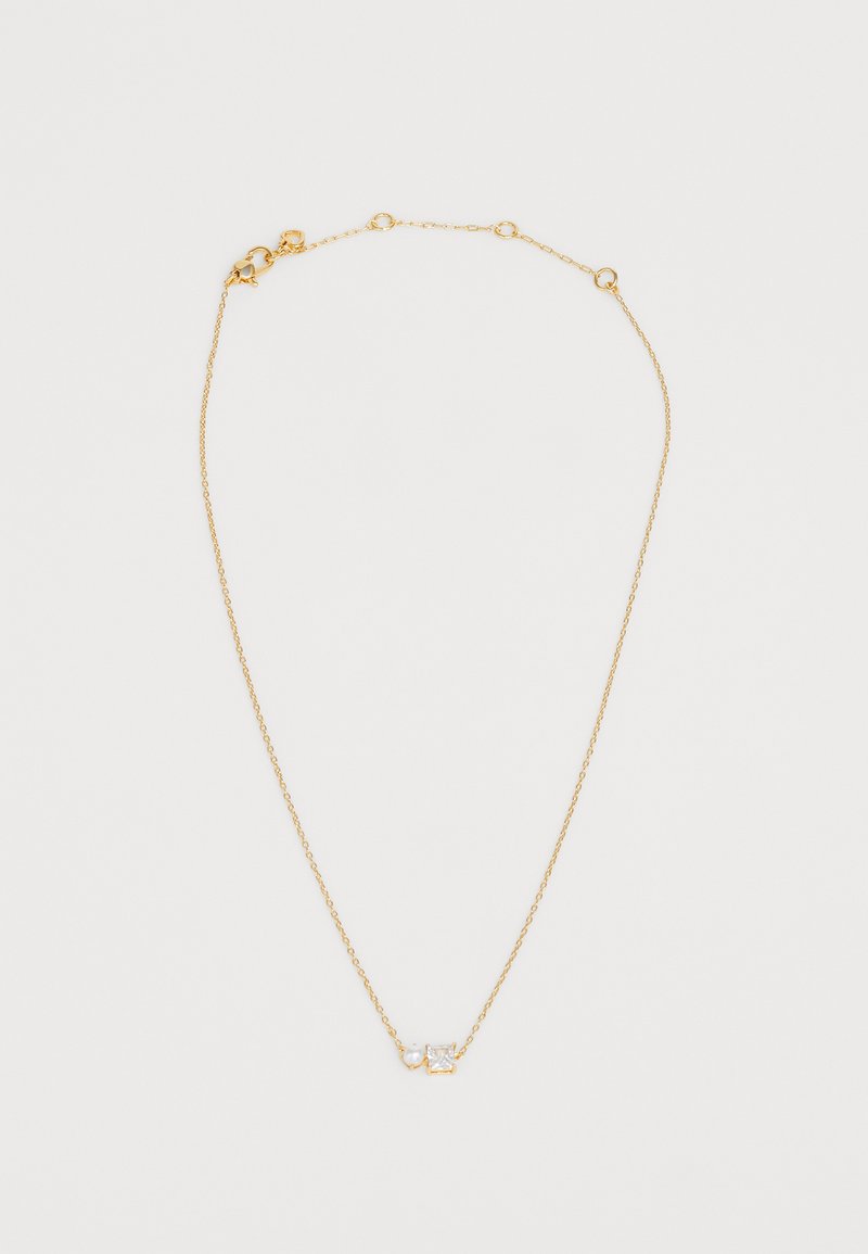 Colar banhado a ouro com uma corrente delicada, apresentando um detalhe em zircão cúbico. O design inclui duas pedras transparentes com formas variadas.