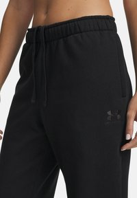 Black sweatpants with elastic waistband and adjustable drawstring. Features soft texture and embroidered logo on the left thigh.