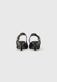 Schwarze High Heels Sandalen mit einem strukturierten Stoff an der Seite, offener Ferse und einer metallischen Schnalle am Knöchelriemen. Oben aus glattem Leder.