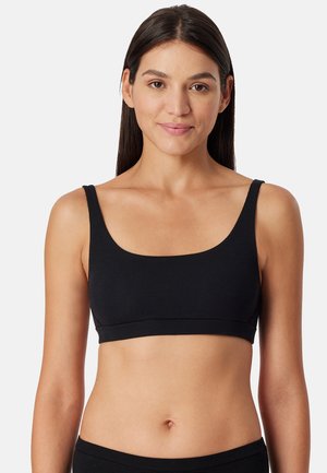 Bralette nera a costine con spalline larghe e scollatura a forma di semicircolo, caratterizzata da un bordo senza cuciture nella parte inferiore e una consistenza liscia.