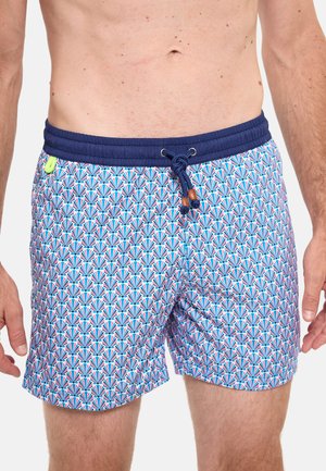 Homme portant un short de bain à motifs avec une ceinture bleu marine et un cordon, présentant un motif de éventail géométrique en bleu, rose et blanc.