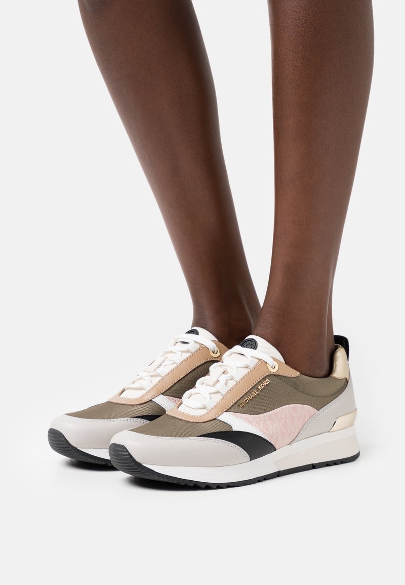 Baskets en matériaux mixtes beige, olive et noir. Présentent un panneau latéral texturé et un logo, avec une semelle amortie et une fermeture à lacets.