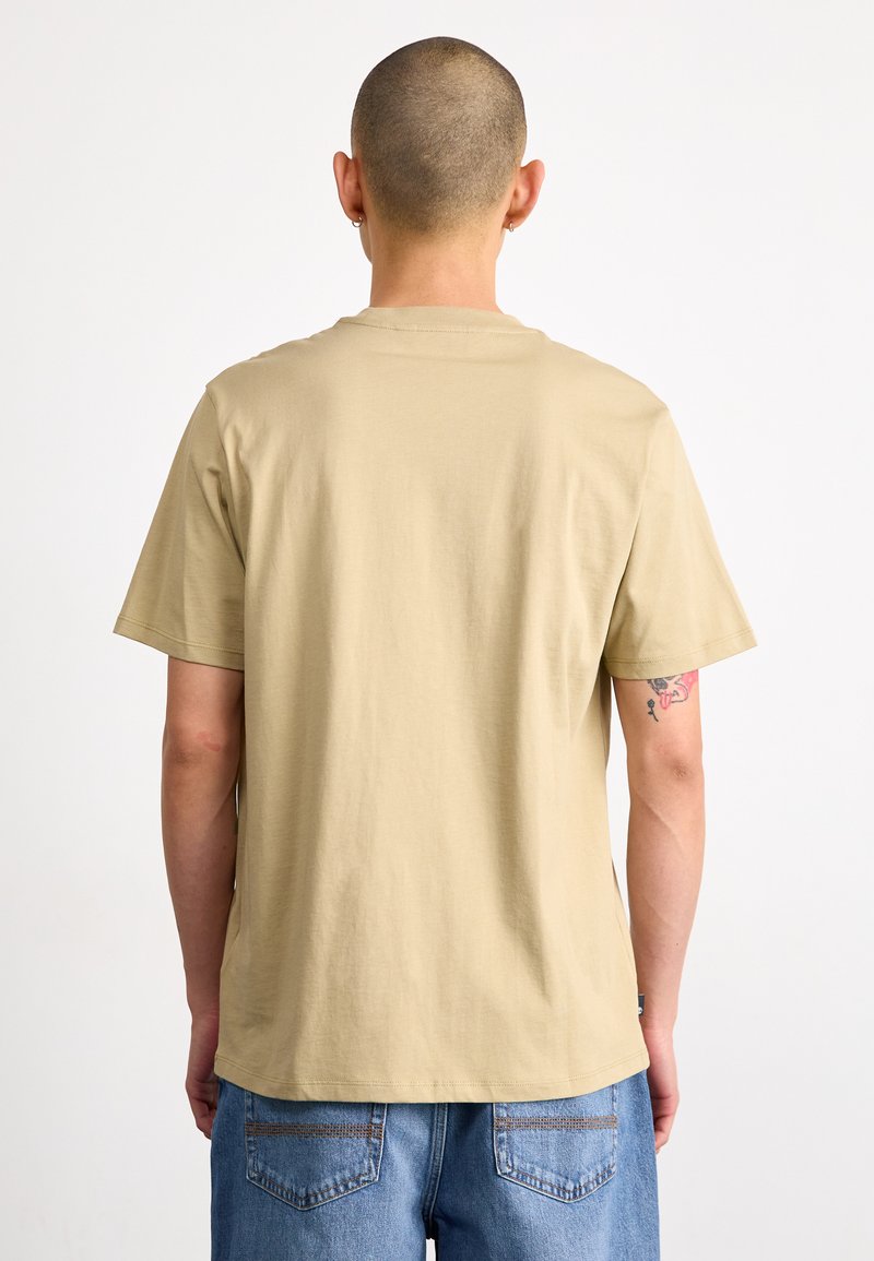 Beige Kurzarm-T-Shirt aus Baumwolle mit lockerer Passform. Es zeigt einen schlichten Rücken mit minimalen Nähten und weicher Textur.