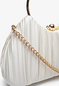 Sac à main en satin blanc plissé avec une chaîne en or et un cadre arrondi. Présente un détail d'accent noué en haut pour la fermeture.