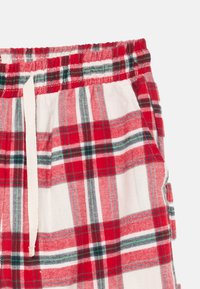 Red, white, and green plaid drawstring shorts with elastic waistband and side pockets on a white background.