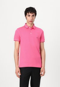 Rosa kortärmad polotröja med vit krage och ärmstripes. Strukturerad bomullstyg med en liten logotyp på vänster bröst.