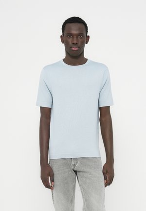 T-shirt a maniche corte color azzurro chiaro realizzata in tessuto morbido con scollo rotondo; design semplice e texture liscia. Indossata con jeans grigio chiaro.