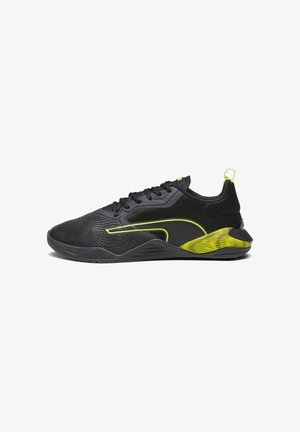 Chaussure de sport noire avec lacets noirs, lignes d'accent jaune néon, semelle texturée et boucle au talon sur fond blanc.