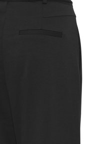 Pantalons noirs en tissu lisse avec une coupe ajustée, des poches latérales et une poche arrière unique avec un détail de bord discret.