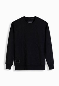 Sweat-shirt noir à manches longues avec col rond, orné d'un motif en relief de lettres et d'un petit patch rectangulaire noir près de l'ourlet inférieur.