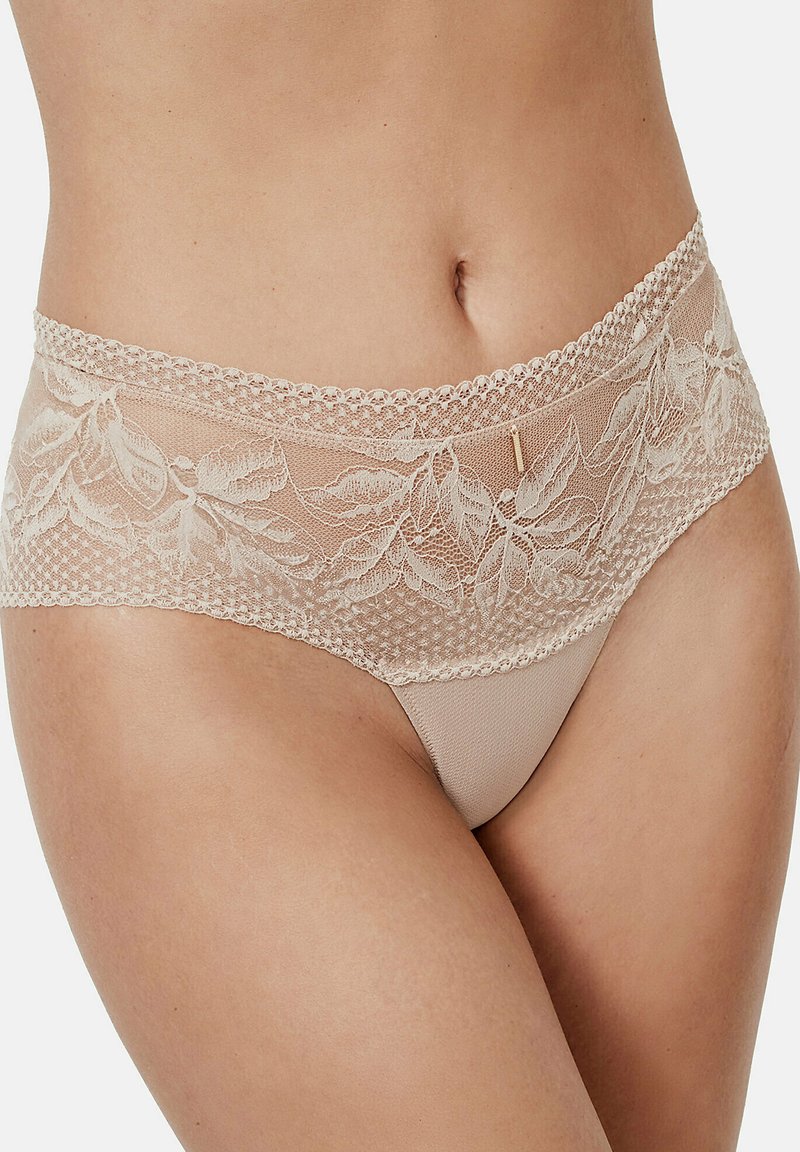 String en dentelle de couleur nude avec un motif floral, en maille texturée et bordure festonnée. Accent doré subtil au niveau de la taille.