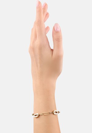 Bracciale dorato con catena intrecciata e accenti decorativi, adagiato su una mano con sfondo neutro.