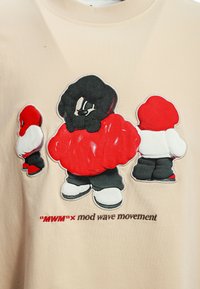 Camiseta beige con tres figuras de estilo caricaturesco vestidas con trajes estilizados: acentos rojos y negros, textura brillante y el texto "MWM x mod wave movement."