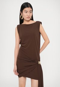 Pruun varrukateta kleit volditud kangaga, millel on puusaalune sõlmedetail ja kuldne aksent, valmistatud pehmest, venivast materjalist.