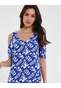 Blusa floral azul con mangas cortas, con patrones de hojas blancas. Escote en forma de V y hombros descubiertos, hecha de tela ligera.
