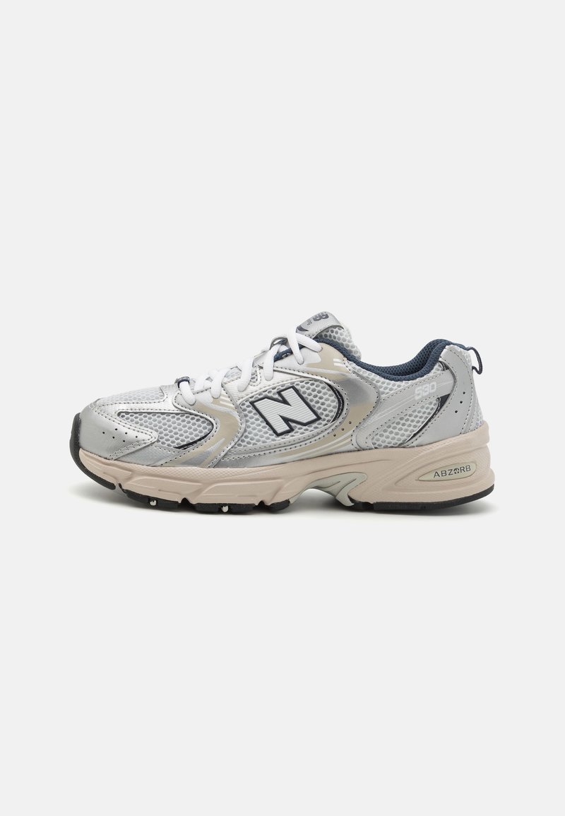 Chaussure de sport New Balance gris clair et beige avec tige en mesh, fermeture à lacets et accents noirs sur la semelle, vue de côté.