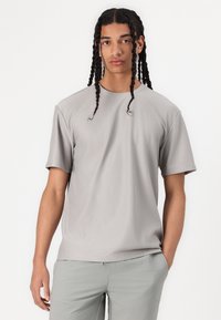 Grå stribet t-shirt med korte ærmer, rund halsudskæring og afslappet pasform. Modellen har lysegrå bukser på. Ensartet baggrund.