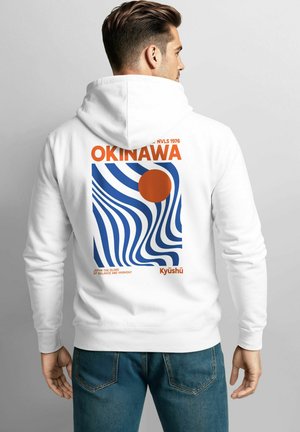 Weiße Kapuzenjacke mit einem lebendigen Grafikdruck, der blau-orange Muster zeigt, mit dem Text "OKINAWA" und einer stilisierten roten Sonne.