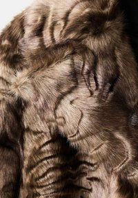 Cappotto in finta pelliccia nei toni del marrone, caratterizzato da un motivo testurizzato di linee ondulate e una superficie morbida e pelosa con una finitura densa e lussuosa.