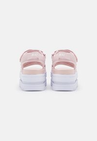 Rosa Nike-sandaler med justerbara remmar, tjock vit sula, öppen baksida och logodetalj. Texturerat material ger bra grepp.