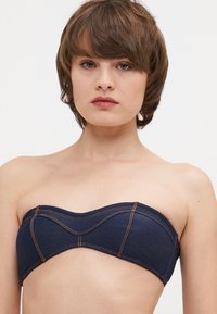 Temno modra denim brez naramnic bandeau bluza s ukrivljenimi šivi in kontrastnim oranžnim šivanjem, ki se ponaša z gladko teksturo in strukturirano zasnovo.