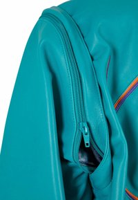 Rukáv tyrkysové kožené bundy s exponovaným zipem a vnitřní kapsou, s kontrastními oranžovými a fialovými akcenty na látce.