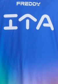 Maglietta a gradiente blu con logo bianco "FREDDY" in alto e testo stilizzato "ITA", realizzata in un tessuto liscio e leggero.