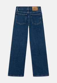 Jeans de pierna ancha en azul oscuro, hechos de denim, con un parche de marca de cuero en la parte trasera de la cinturilla y dos bolsillos traseros con costuras en ángulo.