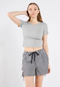 Gray cropped T-shirt in a ribbed material paired with black and white checkered shorts featuring an elastic waistband and drawstring ties.