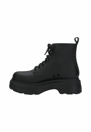 Botte de combat noire à lacets avec semelle épaisse compensée et languette à l’arrière, vue de profil droit sur fond blanc.