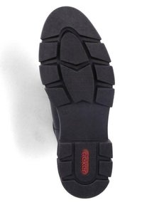 Melnas gumijas kurpju zoles ar teksturētu rakstu, kurai ir dziļi protektori un sarkana emblēma. Dizainā ir iekļautas stūrainas iegriezumi, kas nodrošina saķeri.