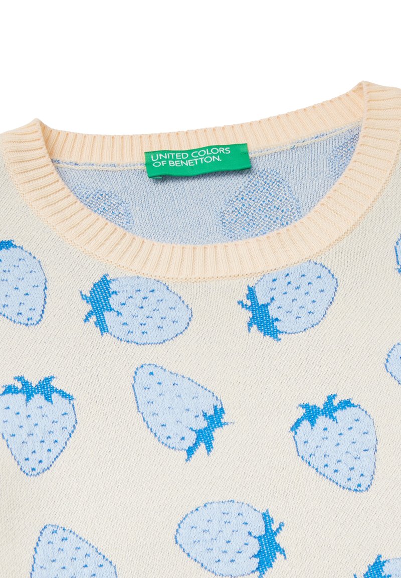 Jasna beżowa sweter z niebieskim wzorem truskawek, zaokrąglony ściągaczowy dekolt i metka z napisem "United Colors of Benetton."