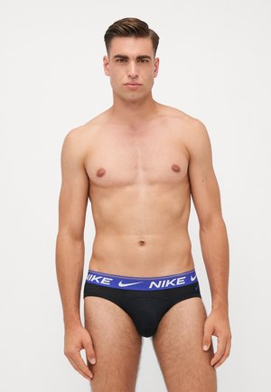 Schwarze Unterhosen mit einem breiten blauen Bund und weißem "NIKE"-Logo; glatte Textur, enge Passform, Fronttaschendetail und minimalistisches Design.