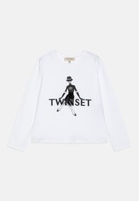 White long-sleeve shirt featuring a black graphic design of a figure in a dress, with "TWINSET" text below. Cotton material, relaxed fit.