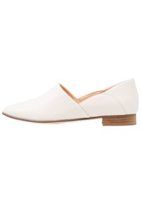 Chaussure plate en cuir blanc avec un bout pointu et un petit talon en bois. Présente une découpe en forme de V sur le côté pour un design supplémentaire. Texture lisse.
